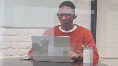 Kulaklıklı Afrikalı Çağrı Merkezi 'nde dizüstü bilgisayarda çalışıyor.