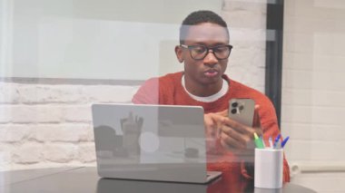 Dizüstü bilgisayarlı Afrikalı Adam Telefonu Kullanıyor