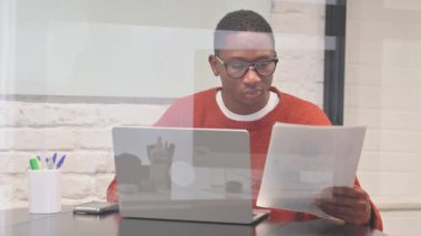 Belgeler ve Laptop üzerinde çalışan Afrikalı Adam