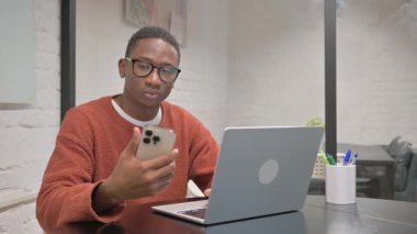 Dizüstü bilgisayarlı Afrikalı Amerikalı Adam Telefonu Kullanıyor