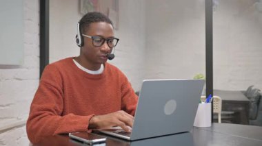 Kulaklıklı Afro-Amerikan Adam Dizüstü bilgisayar kullanıyor.