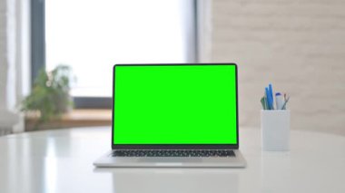 Laptop with Green Screen on Desk in Office