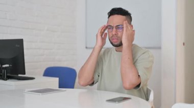 Baş ağrısı olan İspanyol bir adam iş yerinde oturuyor.