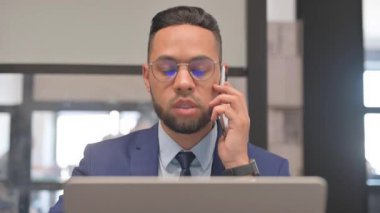 İspanyol iş adamının laptopta çalışırken müşteriyle telefonda konuşmasını kapat.