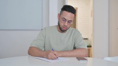 Orta yaşlı adam ofiste otururken yazıyor.