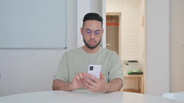 Orta yaşlı adam telefonuyla görüntülü konuşma yapıyor.