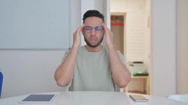 Baş ağrısı olan orta yaşlı bir adam iş yerinde oturuyor.