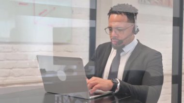 Çağrı Merkezi 'nde kulaklığı olan İspanyol İşadamı Laptop' ta daktilo kullanıyor.