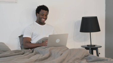 Yatakta Oturan Afrikalı Adam 'ın Dizüstü bilgisayardaki görüntülü sohbeti