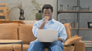 Evde dizüstü bilgisayar kullanan Öksüren Hasta Afrikalı Adam