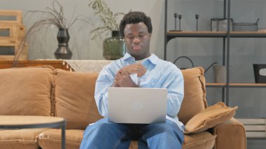 Evde dizüstü bilgisayar kullanan bilek ağrısı olan Afrikalı adam.
