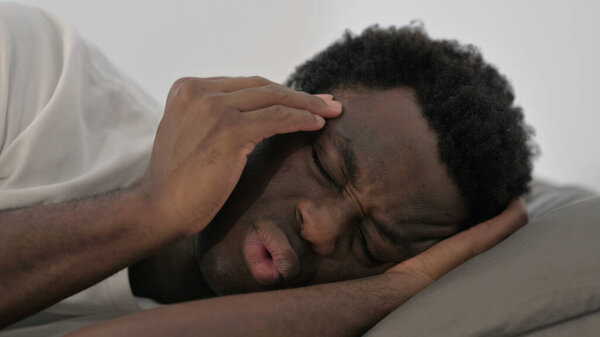 Close up of African Man with Headache Lying on Side in Bed