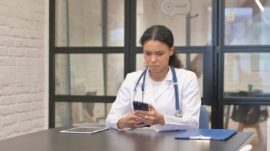 Hastanede akıllı telefon kullanan Afrikalı kadın doktor.