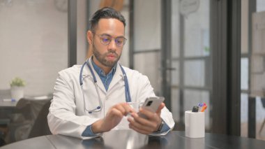 Hastanede akıllı telefon kullanan Afrikalı erkek doktor.