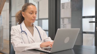 Dizüstü bilgisayarda yazan çok ırklı kadın doktor.