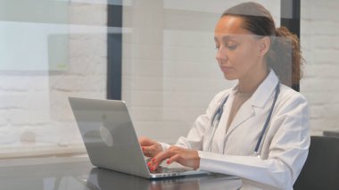 Dizüstü bilgisayarda yazan çok ırklı kadın doktor.