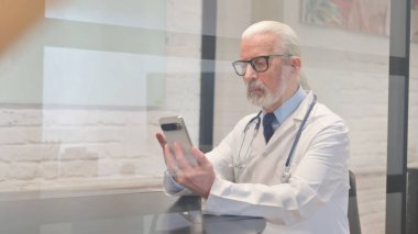 Kıdemli Erkek Doktor İş yerinde Telefon Kullanıyor