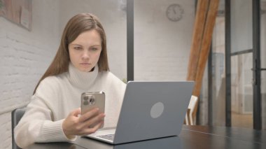 Dizüstü bilgisayarlı Genç Kadın Telefonu Kullanıyor