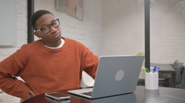 Sırt ağrısı olan Afrikalı Amerikalı Laptop üzerinde çalışıyor
