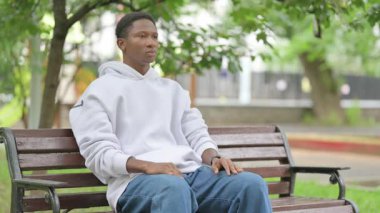 Sıradan bir Afrikalı Amerikalı Park Bench 'ten uzaklaşmayı bekliyor.