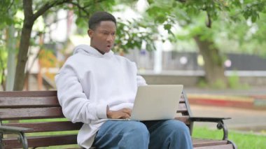Park Bench 'te dizüstü bilgisayar kullanan Kafası Karışık Afro-Amerikan Adam