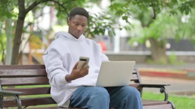 Akıllı Telefon ve Laptop kullanan sıradan bir Afrikalı Amerikalı.