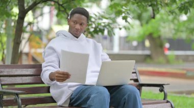 Açık havada dizüstü bilgisayarla Belgeleri Kutlayan Afro-Amerikan Adam 'ınız kutlu olsun.