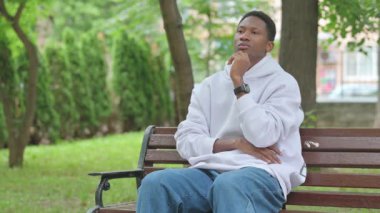 Bench 'te oturan dalgın Afrikalı genç adam.