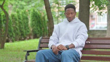 Genç Afrikalı Park Bench 'te Akıllı Saat Kullanıyor