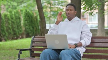 Bench 'te dizüstü bilgisayar kullanan boynu ağrıyan genç Afrikalı adam.