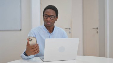 Akıllı telefon ve dizüstü bilgisayar kullanan Afrikalı Amerikalı İşadamı