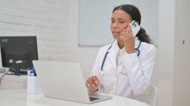 Bilgisayarda çalışırken telefonda konuşan Afrikalı Kadın Doktor