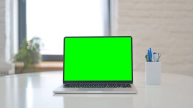 Laptop with Green Screen on Desk in Office