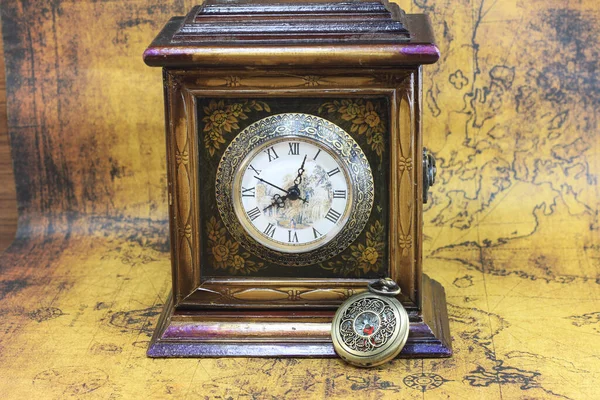 コンパスと時計を備えた観光の象徴として コンパスと時計で旅行し コンパスと時計と研究と時計で世界の古いヴィンテージ地図上の古典的なラウンドコンパスと古いヴィンテージクロックと本 — ストック写真