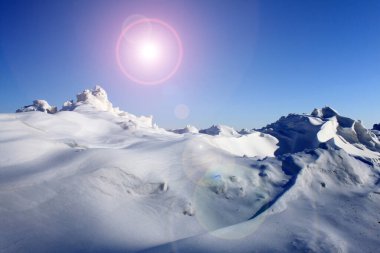 Mavi gökyüzüne karşı parlak kar yağışı olan güzel kış manzarası ve alışılmadık soyut güneş ışığı