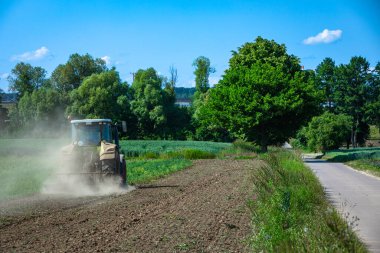 Kurak bir yaz gününde traktör çiftlikte çalışıyor.