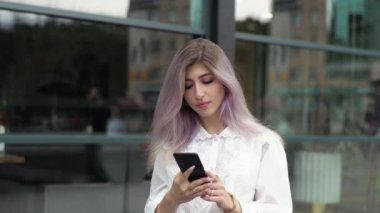 Genç bir iş kadını pencerenin arkasında duruyor, cep telefonuyla konuşuyor..