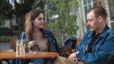 Genç bir çift. Denim giysileri. Eski bir restoranda randevuda, dışarıda. Konuşuyorlar..