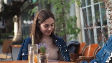 Genç bir çift. Denim giysileri. Eski bir restoranda randevuda, dışarıda. Konuşuyorlar..