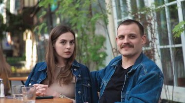Genç bir çift. Denim giysileri. Eski bir restoranda randevuda, dışarıda. Konuşuyorlar..