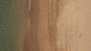 Güzel kumlu sahil manzarası. Turkuvaz deniz dalgalarıyla kıyı şeridi. Sarı kum plajı ve su yüzeyi dokusunun güzel hava aracı görüntüsü.