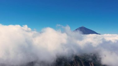 Teide Ulusal Parkı 'nın havadan 4K görüntüsü ve Teide Dağı beyaz kabarık bulutlar denizi üzerinde. İspanya 'nın Tenerife adasındaki Teide Ulusal Parkı' nda yanardağ.