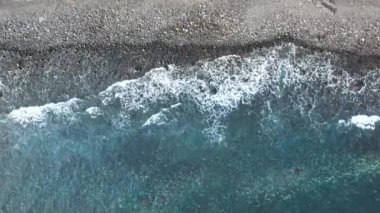 Güzel kumlu sahil manzarası. Turkuvaz deniz dalgalarıyla kıyı şeridi. Sarı kum plajı ve su yüzeyi dokusunun güzel hava aracı görüntüsü.