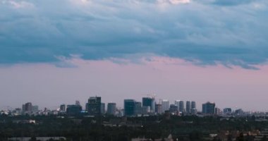 Cityscape sunset time lapse. The silhouettes of skyscrapers and urban buildings against the background of clouds. City modern intensive life.
