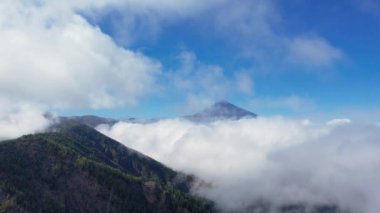 Teide Ulusal Parkı 'nın havadan 4K görüntüsü ve Teide Dağı beyaz kabarık bulutlar denizi üzerinde. İspanya 'nın Tenerife adasındaki Teide Ulusal Parkı' nda yanardağ.