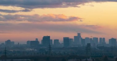 Cityscape sunset time lapse. The silhouettes of skyscrapers and urban buildings against the background of clouds. City modern intensive life.