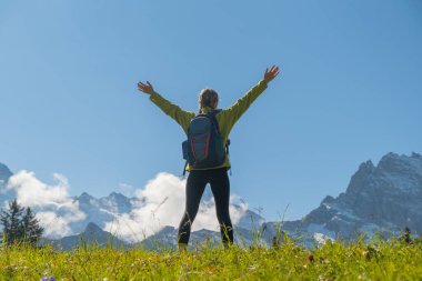 Kar dağlarının önünde duran ve İsviçre manzarasının tadını çıkaran sportif bir kadın. Gezgin şehvet, spor, doğadaki güzellik..