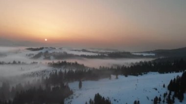 Karpatya dağlarının üzerindeki sis ve bulutlara insansız hava aracı görüntüsü. Güneşli kış, dondurucu soğuk.