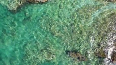 4k Aerial üst turkuaz deniz dalgaları uçurumda kırılıyor. Küçük sıcak dalgalar, sakinlik ve rahatlama. Açık mavi su.
