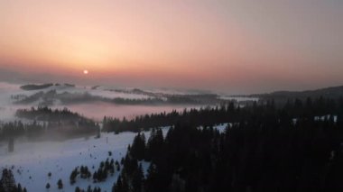 Karpatya dağlarının üzerindeki sis ve bulutlara insansız hava aracı görüntüsü. Güneşli kış, dondurucu soğuk.